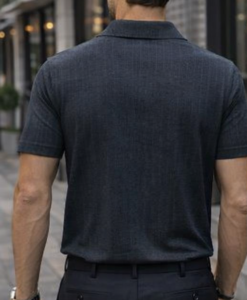 Man wearing a dark polo shirt and pants walking on a street.