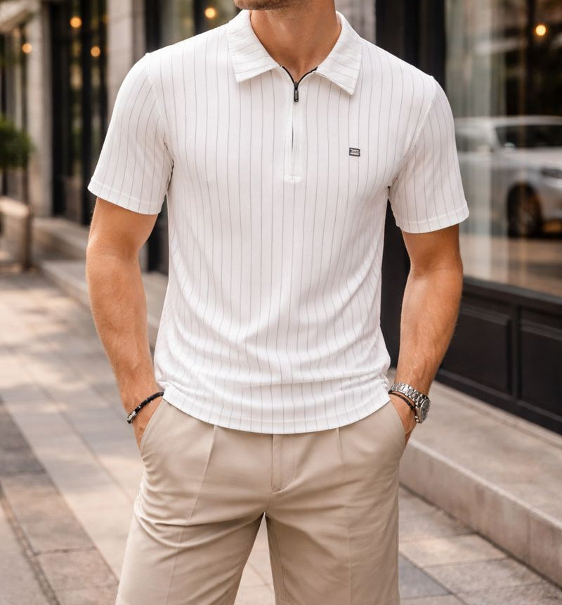 Man wearing a white polo shirt and beige shorts standing on a city street.