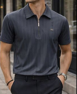 Man wearing a dark blue striped polo shirt with a brand logo, standing outdoors.