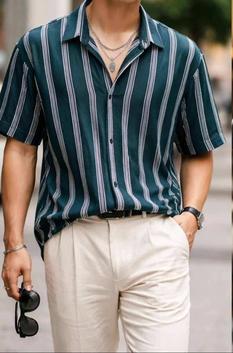Person wearing a green and white striped shirt with beige pants, standing outdoors.