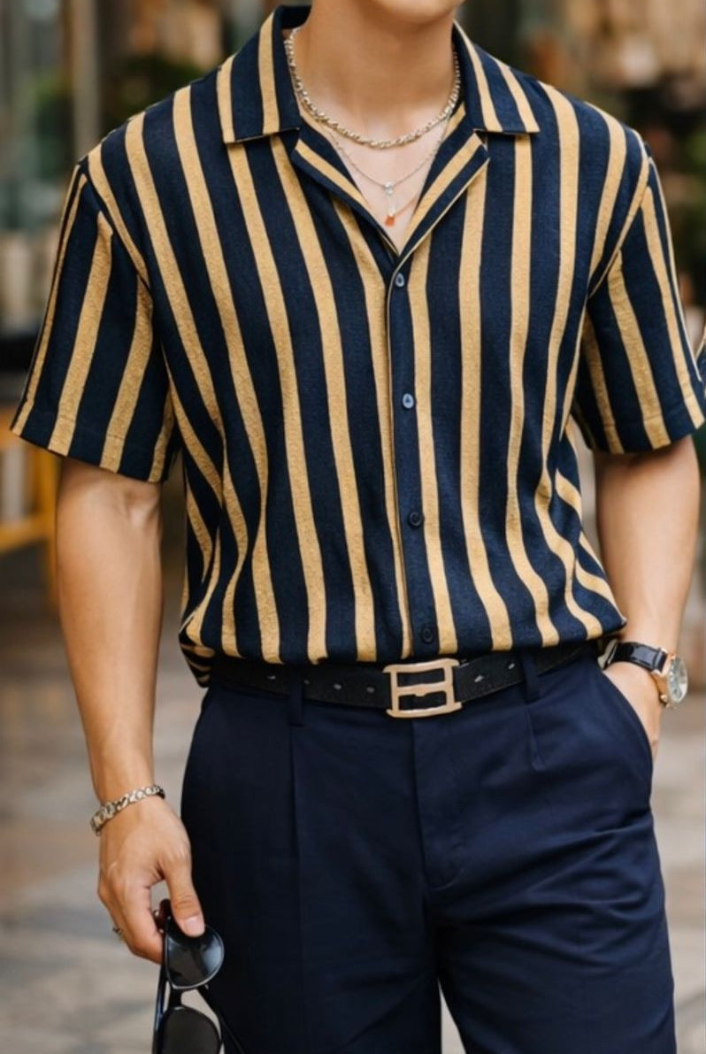 Person wearing a navy and beige striped shirt with dark pants, standing outdoors.