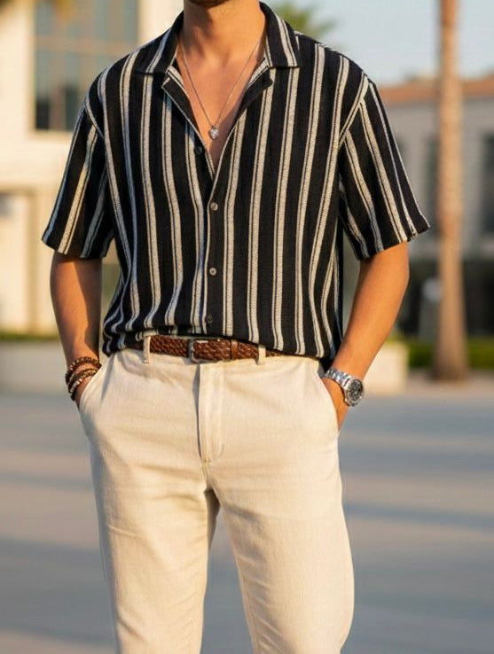 Person wearing a black and white striped shirt with beige pants outdoors.