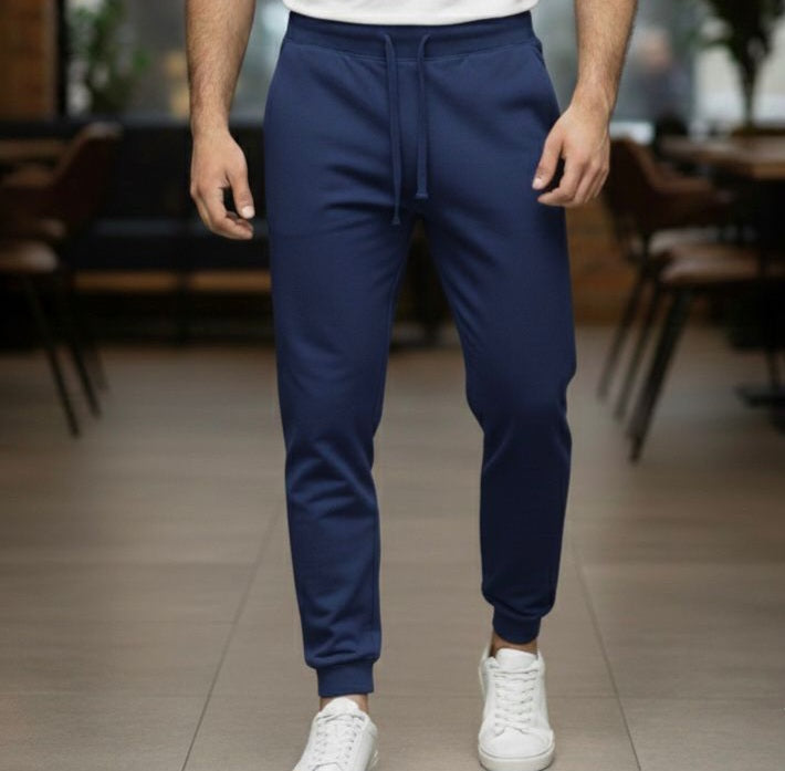 Person wearing blue jogger pants and white sneakers in a blurred indoor setting