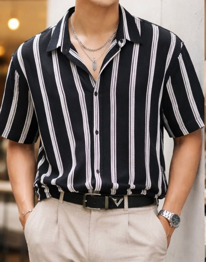 Man wearing a black and white striped shirt with beige pants in an indoor setting