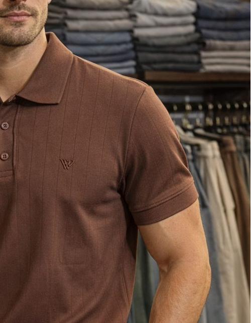 Man wearing a brown polo shirt and beige pants in a clothing store.